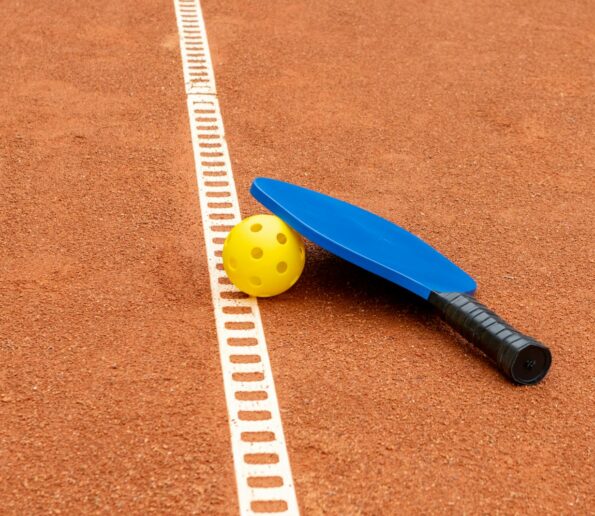a tennis racket and ball on a clay court